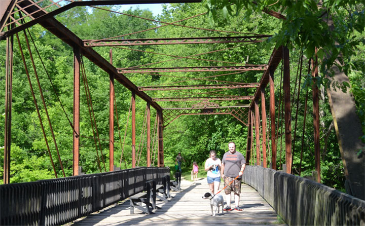 two people walking their dog across a beautiful wood bridge